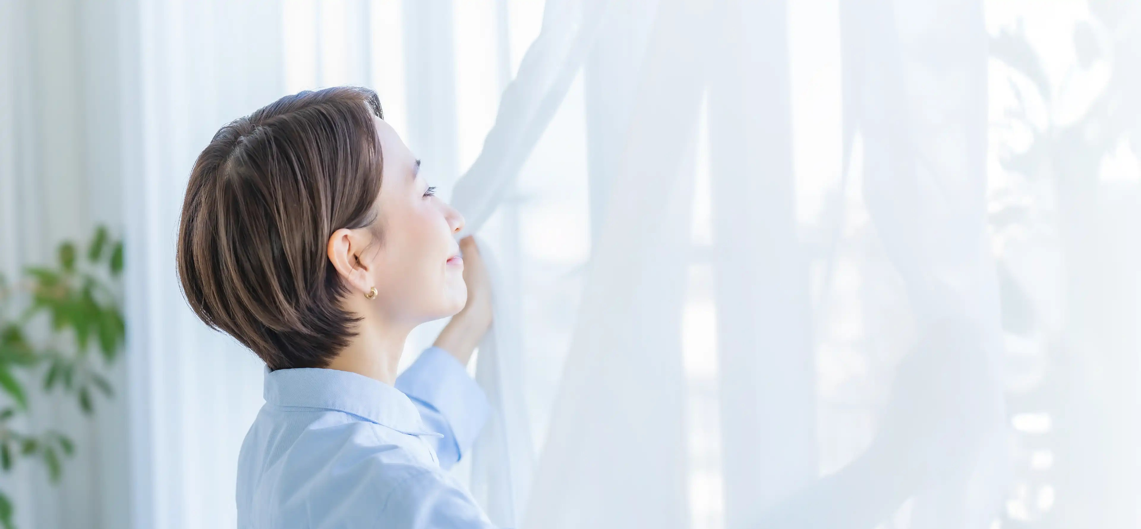 部屋の窓越しに日差しを浴びる人